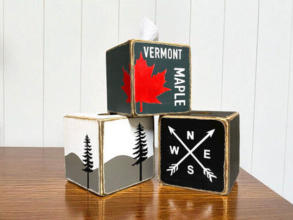 Rustic wooden tissue box covers with Vermont maple leaf design, compass arrows, and mountain tree silhouette artwork, farmhouse cabin style home décor