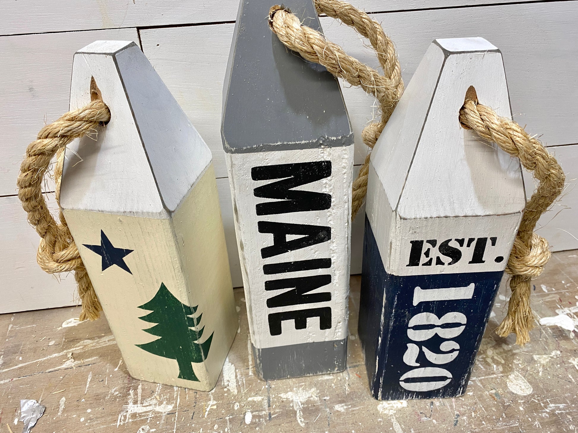 Detailed view of decorative Maine wood buoy set with painted flag design, weathered finish, and handmade nautical details. Coastal decor for beach houses, cottages, and New England homes