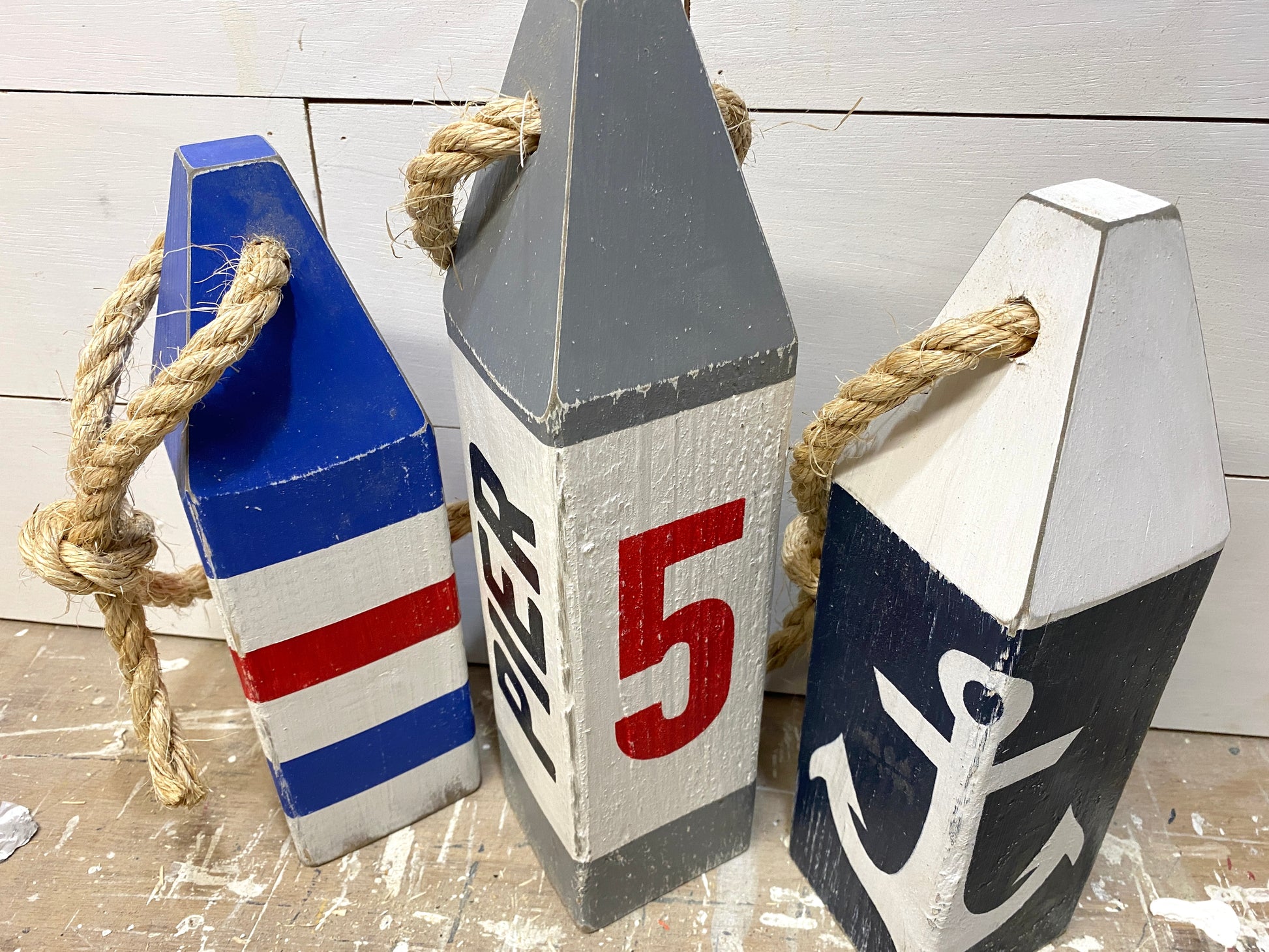 Close up of Pier 5 nautical wood buoy featuring hand-painted anchor design and distressed wood finish. Coastal decor for beach houses, coastal homes, waterfront cottages, boating spaces, sailing gifts, harbor decor, and New England nautical style.