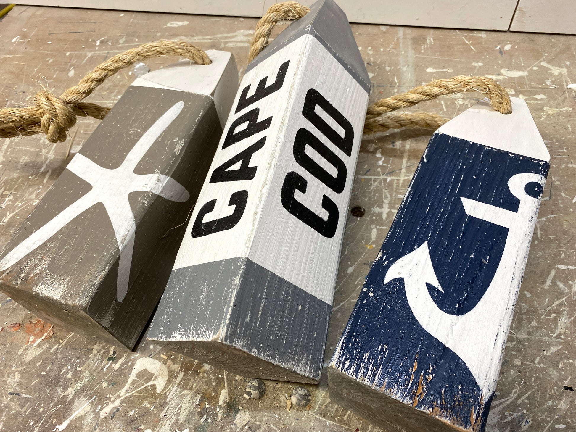 Close-up of Cape Cod nautical wood buoys showing hand-painted starfish and anchor details, distressed finish, and rustic coastal style. Beach house decor, coastal cottage decor, nautical room decor, seaside home accent, and ocean-inspired decor