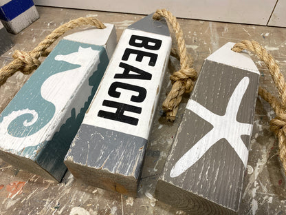 Close-up of seahorse and starfish nautical buoys showing hand-painted details, rustic wood texture, and coastal decor style. Perfect for beach house decor, cottage decor, and coastal rooms