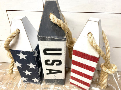 Close-up of decorative American flag nautical buoy showing hand-painted stars and stripes, rustic wood texture, and distressed coastal finish. Perfect for patriotic decor, beach house decor, boating, sailing, and coastal homes