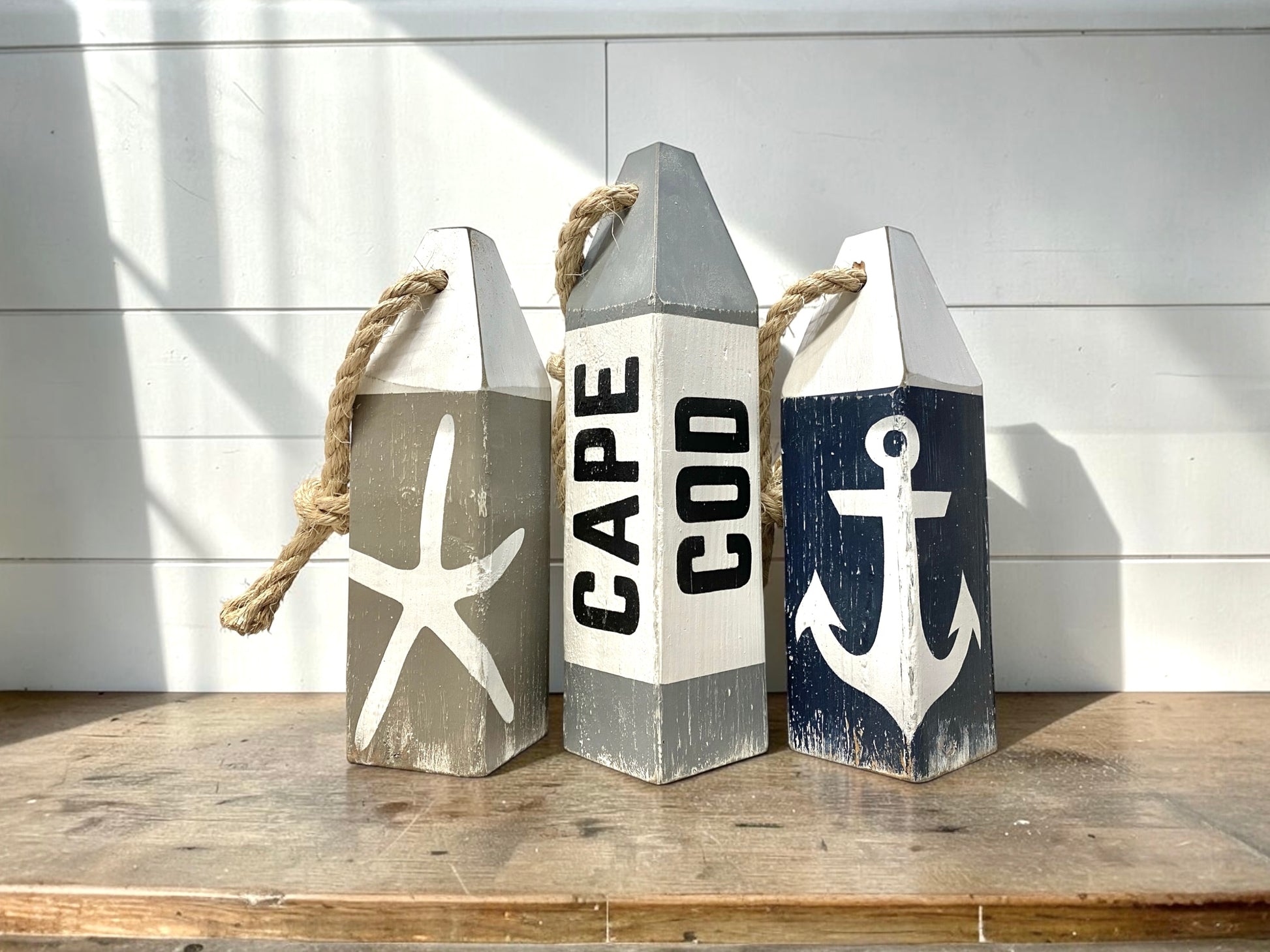 Cape Cod buoy set displayed in a coastal home with nautical decor. Handmade wood accents inspired by coastal cottages, beach houses, harbors, and classic New England seaside style.