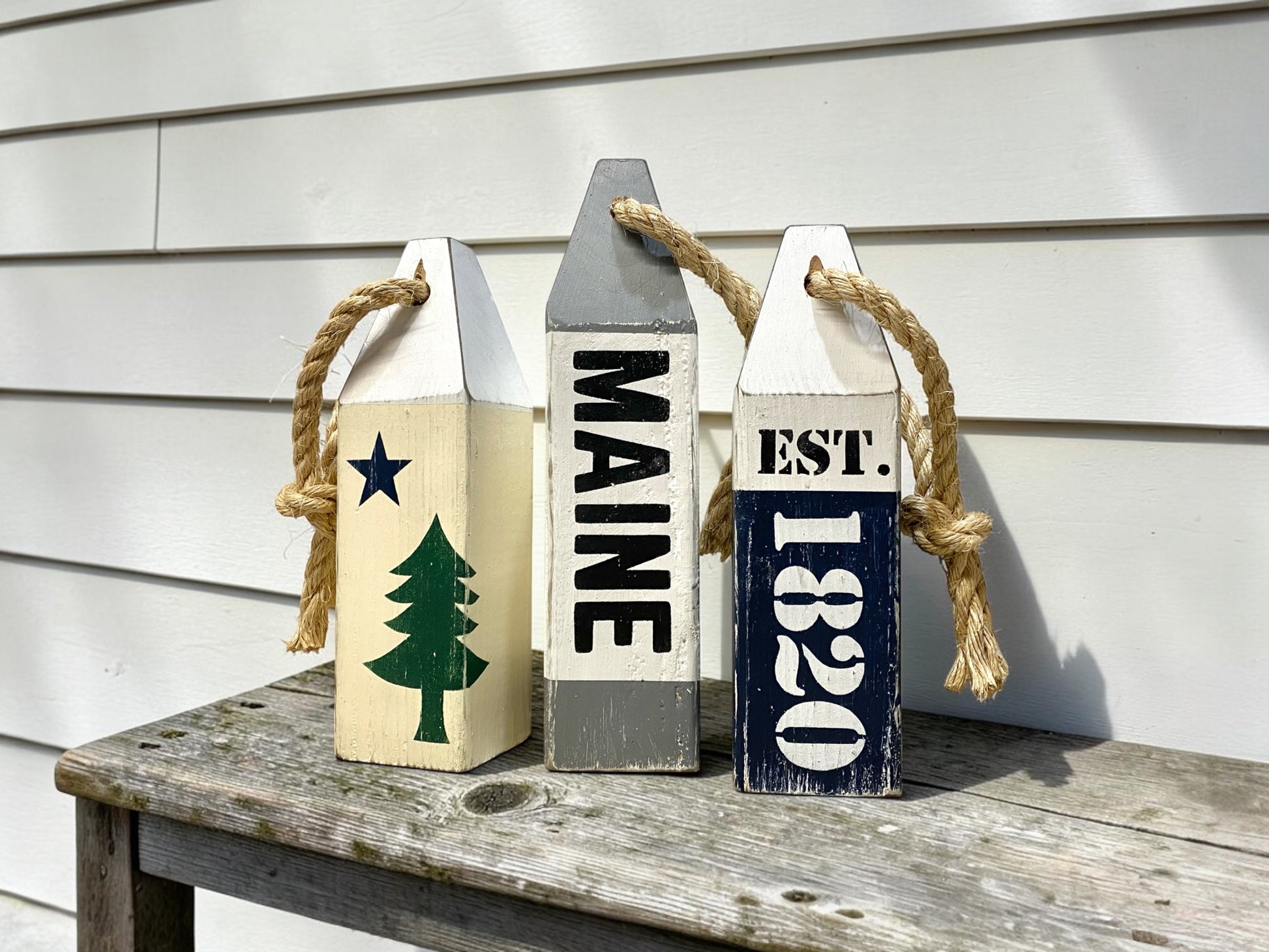 Decorative Maine wood buoy set displayed in a  nautical space. Handmade coastal accents featuring the original Maine flag design, perfect for beach houses, coastal cottages, seaside rooms, harbor-inspired spaces, and New England homes.