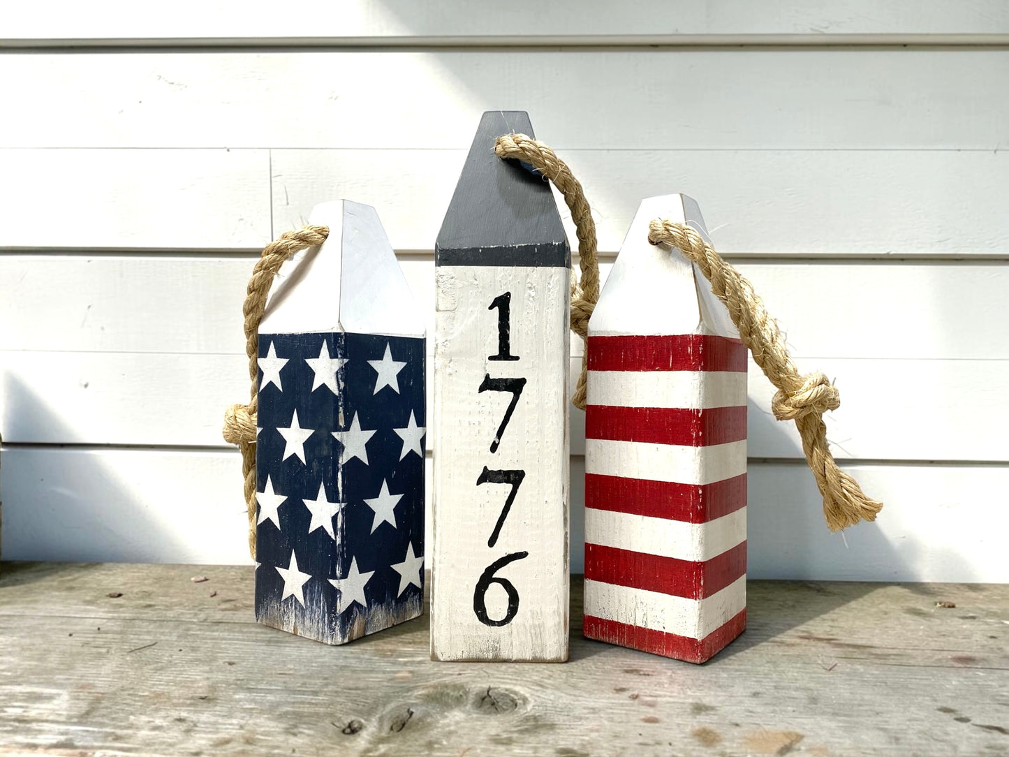 Decorative 1776 patriotic buoy set displayed in a beach house with nautical decor. Handmade coastal accents for beach houses, seaside cottages, ocean-inspired rooms, and waterfront retreats