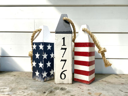Decorative 1776 patriotic buoy set displayed in a beach house with nautical decor. Handmade coastal accents for beach houses, seaside cottages, ocean-inspired rooms, and waterfront retreats