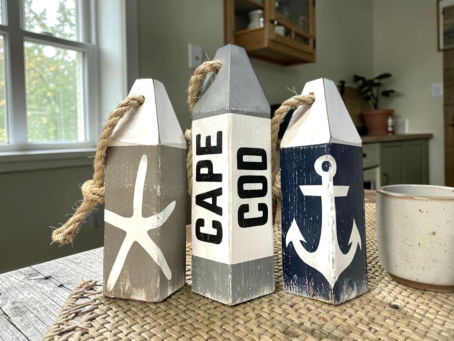 Hand-painted Cape Cod nautical buoy decor featuring starfish, anchor, and rustic coastal details. Coastal home decor for beach-themed rooms, seaside cottages, and ocean-inspired spaces.