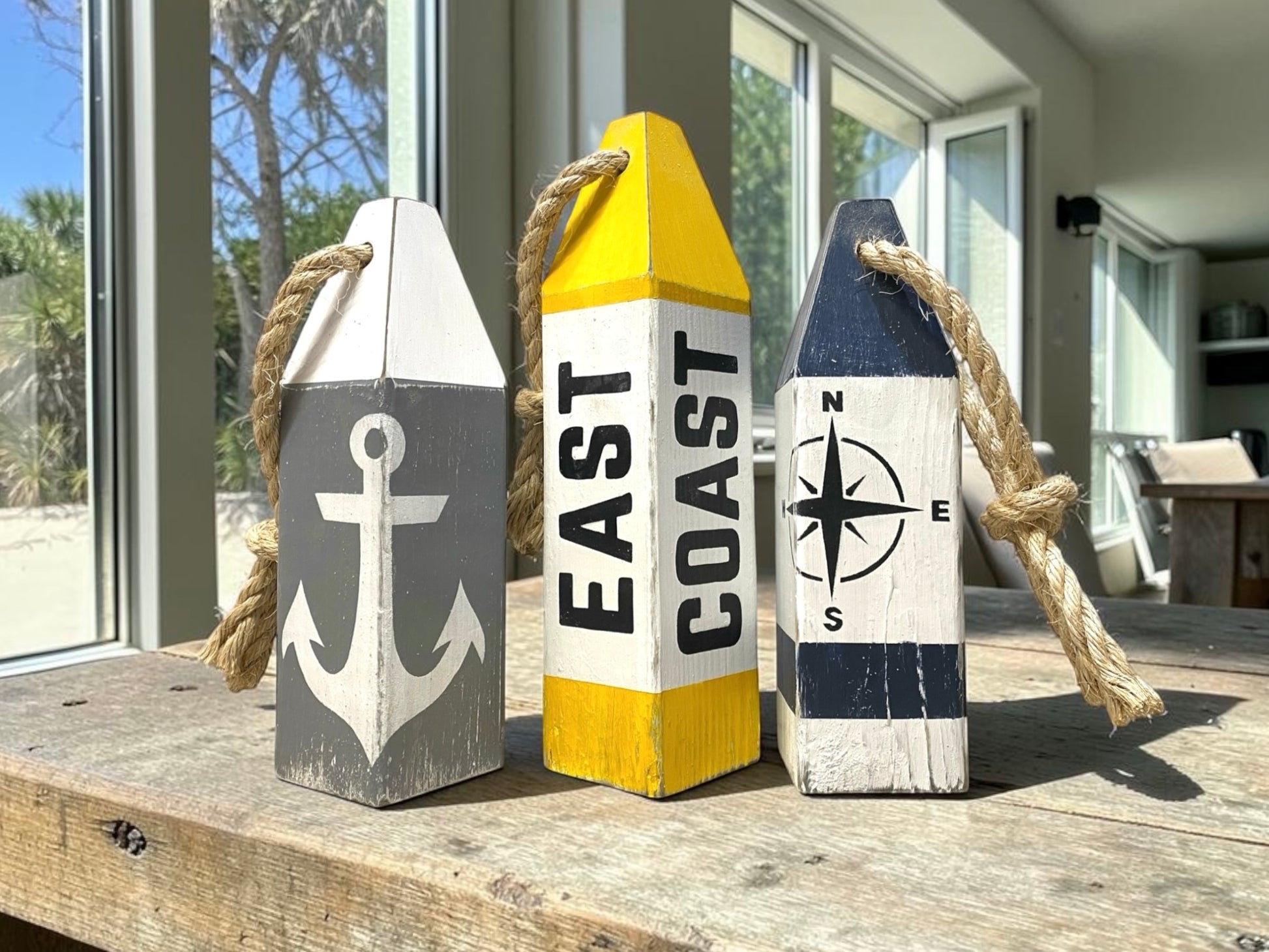 Decorative East Coast nautical buoy set displayed in an ocean-inspired home with coastal decor. Handmade wood accents featuring compass rose and anchor designs, perfect for beach houses, seaside cottages, coastal rooms, waterfront homes, and nautical spaces
