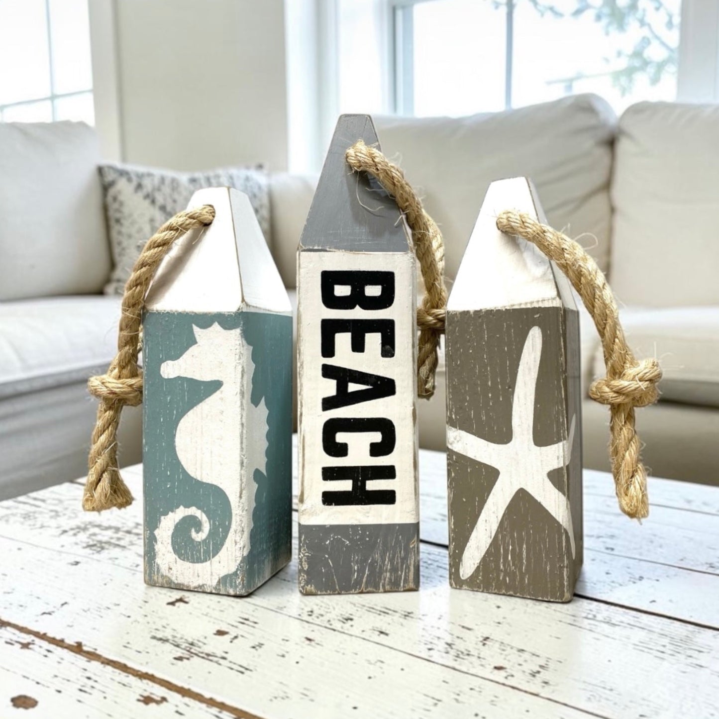 Hand-painted beach wood buoy set featuring seahorse and starfish designs with a distressed finish. Nautical coastal decor for beach houses, coastal cottages, beach-themed rooms, seaside homes, and ocean-inspired spaces