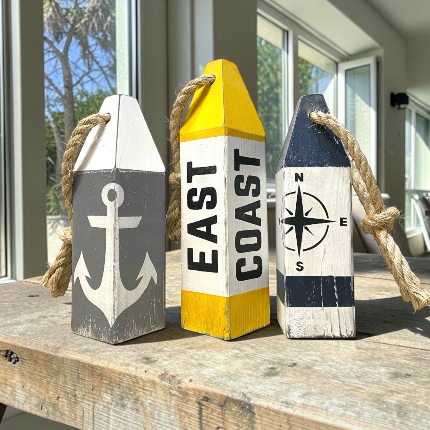 Decorative East Coast wood buoy set featuring compass rose and anchor designs with a distressed finish. Nautical coastal decor for beach houses, coastal cottages, seaside rooms, boating spaces, and waterfront homes