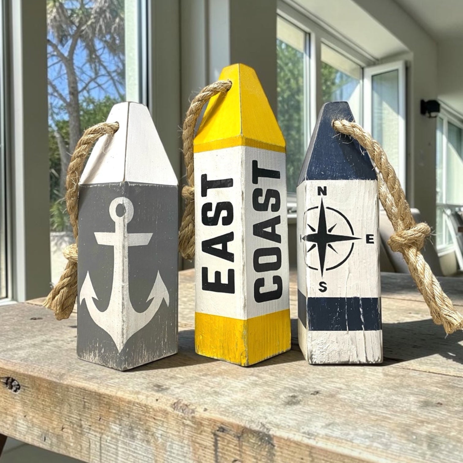 Decorative East Coast wood buoy set featuring compass rose and anchor designs with a distressed finish. Nautical coastal decor for beach houses, coastal cottages, seaside rooms, boating spaces, and waterfront homes