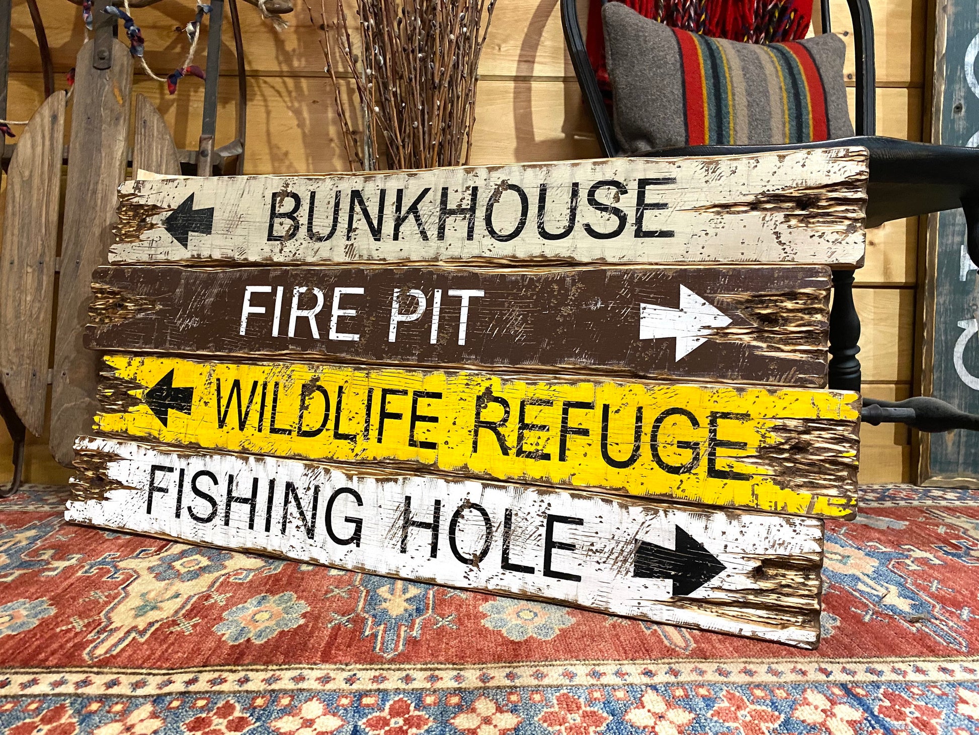 Rustic wooden sign featuring “Bunkhouse, Fire Pit, Wildlife Refuge, and Fishing Hole” — distressed arrow design perfect for cabin, camp, or lodge wall décor, handmade in Maine.