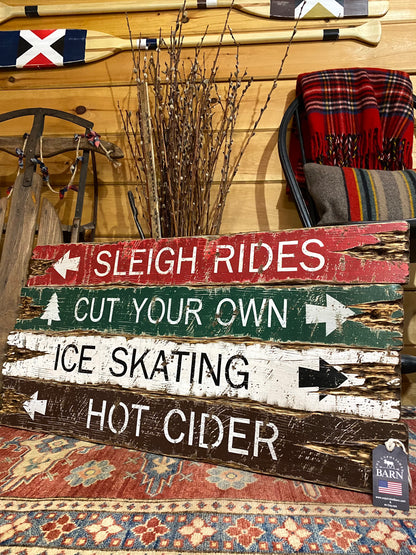 Rustic winter farmhouse sign with distressed wood planks reading “Sleigh Rides,” “Cut Your Own,” “Ice Skating,” and “Hot Cider,” handmade in Maine — cozy holiday decor perfect for cabins, lodges, and Christmas gatherings.