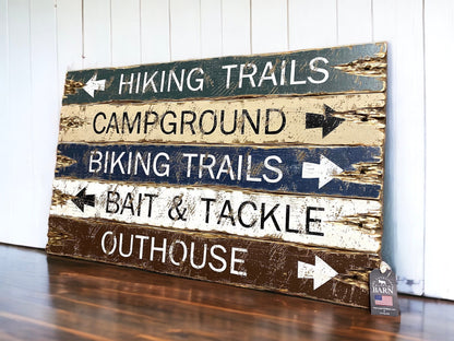 Hand-painted rustic outdoor sign in green, tan, and brown with arrows for Hiking Trails, Campground, Biking Trails, Bait & Tackle, and Outhouse, vintage distressed camping cabin wall art. handmade in Maine 